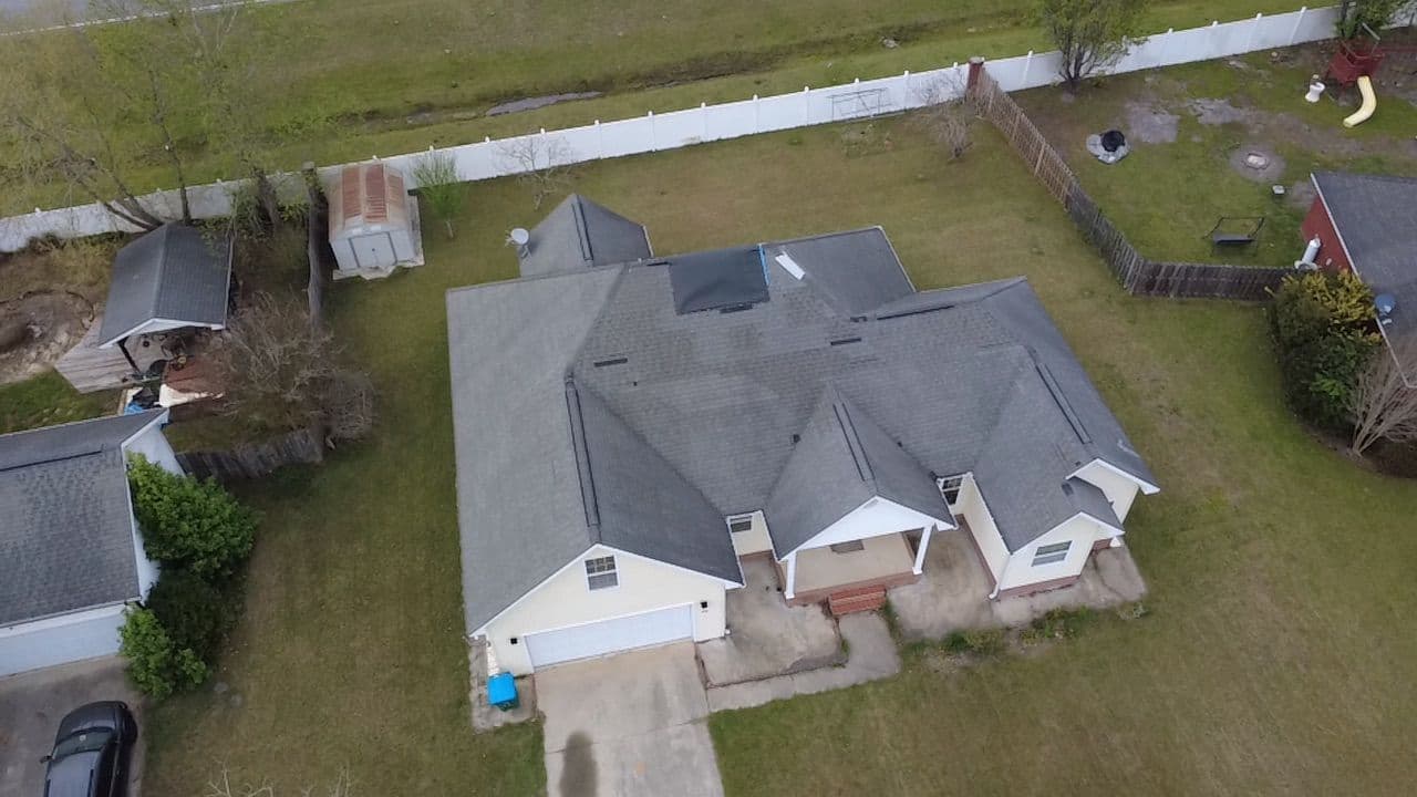 Drone view of a residential home with a newly replaced gray shingle roof