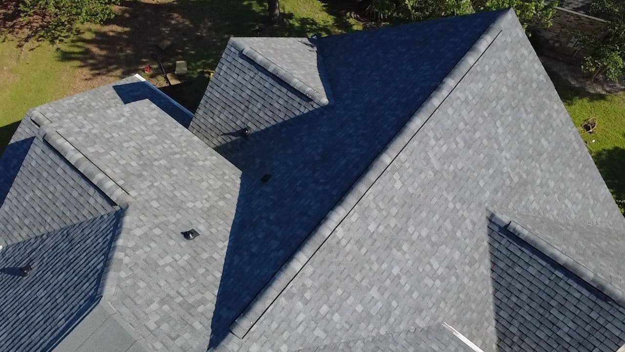 Aerial view of a complex roofline with multiple gables and new shingles